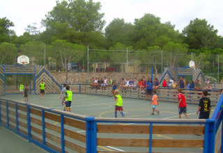 Bambini che giocano a palla su un campo polivalente con spettatori al Camping Vilanova Park, Catalogna, Spagna.