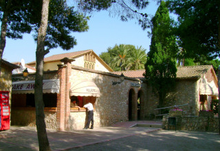 Stenbygget bar og restaurant med træer og palmer i Vilanova Park feriepark, Catalonien, Spanien.
