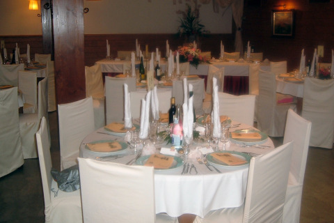 Mesa elegantemente preparada para banquete en Camping Vilanova Park, Cataluña, España, con manteles y sillas blancas.