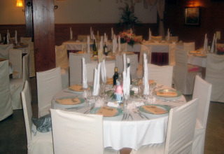 Elegantly set banquet table at Camping Vilanova Park, Catalonia, Spain, with white linens and covered chairs.