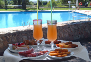 Bevande fresche e antipasti vari su un tavolo vicino alla piscina al Camping Vilanova Park, Catalogna, Spagna.