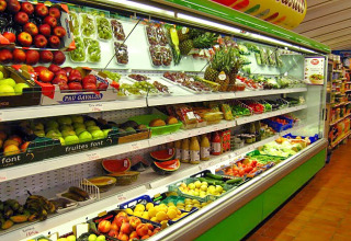 Sección de frutas y verduras en supermercado del Camping Vilanova Park, Cataluña, España, con productos frescos.