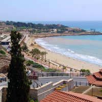 Vista costera cerca de Vilanova i la Geltrú, Cataluña, España, con playa de arena, mar y edificios alrededor.