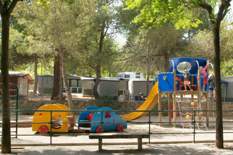 Niños juegan en un parque infantil con tobogán y estructuras coloridas en Camping Vilanova Park, Cataluña, España.