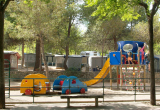 Children play on a playground with a slide and colorful structures at Camping Vilanova Park in Catalonia, Spain.