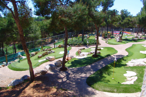 Minigolf immerso tra alberi e sentieri al Camping Vilanova Park, villaggio vacanze in Catalogna, Spagna.