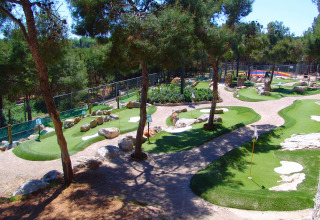 Minigolf immerso tra alberi e sentieri al Camping Vilanova Park, villaggio vacanze in Catalogna, Spagna.