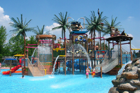 Parc aquatique à Camping Terme Catez en Slovénie avec toboggans, palmiers et enfants jouant dans l’eau.