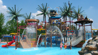 Parque acuático en Camping Terme Catez, Eslovenia, con toboganes, palmeras y niños disfrutando del agua.