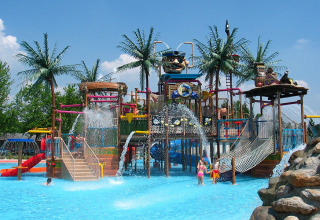 Parque acuático en Camping Terme Catez, Eslovenia, con toboganes, palmeras y niños disfrutando del agua.