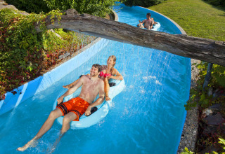 People relaxing on inflatable rings in a lazy river at Camping Terme Catez holiday park in Slovenia.