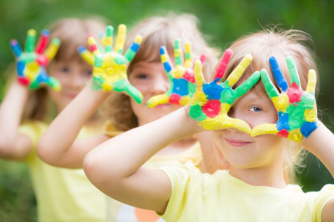 Children play outdoors with colorful painted hands, a fun highlight at Camping Terme Catez in Slovenia.