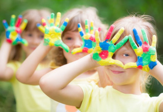 Children play outdoors with colorful painted hands, a fun highlight at Camping Terme Catez in Slovenia.