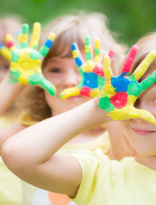 Niños juegan al aire libre con las manos pintadas de colores, una actividad destacada en Camping Terme Catez.