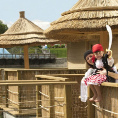 Madre e hijo disfrazados de piratas en una terraza con techo de paja en Camping Terme Catez, Eslovenia.