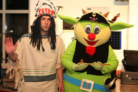 Two people in costume: one in a Native American outfit, one as a green mascot with pirate hat at Camping Terme Catez.