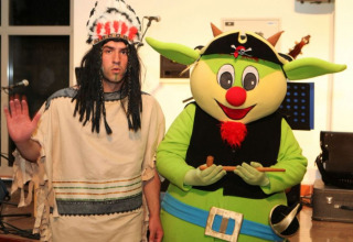 Two people in costume: one in a Native American outfit, one as a green mascot with pirate hat at Camping Terme Catez.