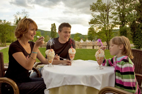 Une famille savoure des coupes glacées en plein air au Camping Terme Catez, en Slovénie, entourée de verdure.