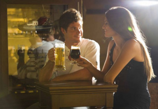 Een jong stel geniet samen van bier in de bar van Camping Terme Catez, Lage Sava, Slovenië, lachend.