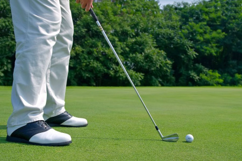 Un golfista con pantaloni bianchi e scarpe nere si prepara a colpire la pallina vicino a Brežice, Slovenia.