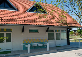 Lavabos exteriores y edificio con tejado rojo en el Camping Terme Catez, parque vacacional en Eslovenia, día soleado.