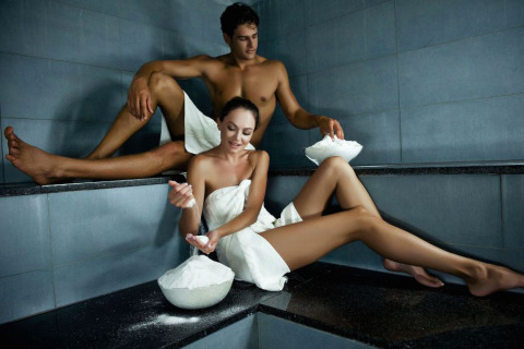 Couple enjoys steam bath at Camping Terme Catez, Slovenia, wearing towels and applying mineral mud.