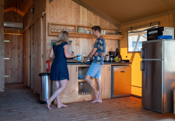 Two people cooking barefoot in a cozy safari tent kitchen at SunLodge Pamoja&Kambi, Camping Terme Catez, Slovenia.
