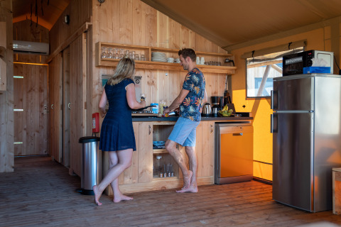 Dos personas cocinan descalzas en la cocina de una tienda safari en SunLodge Pamoja&Kambi, Camping Terme Catez, Eslovenia.