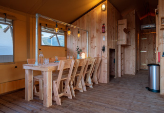Interior de la tienda safari SunLodge Pamoja & Kambi con muebles de madera en Camping Terme Catez, Eslovenia.