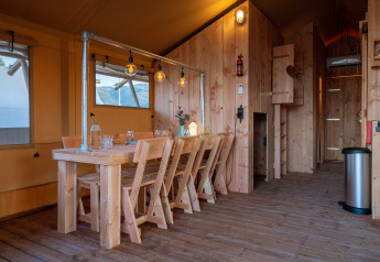 Interior de la tienda safari SunLodge Pamoja & Kambi con muebles de madera en Camping Terme Catez, Eslovenia.