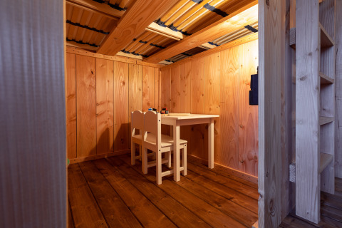 Gezellig houten interieur met een kleine tafel en twee stoelen in een safaritent bij Camping Terme Catez, Slovenië.
