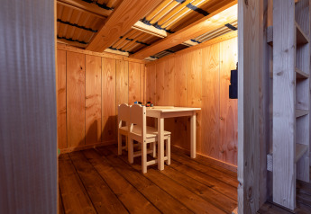 Gezellig houten interieur met een kleine tafel en twee stoelen in een safaritent bij Camping Terme Catez, Slovenië.