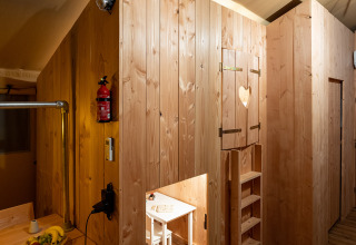 Interior de una tienda safari SunLodge Pamoja&Kambi en Camping Terme Catez, Eslovenia, con muebles de madera.