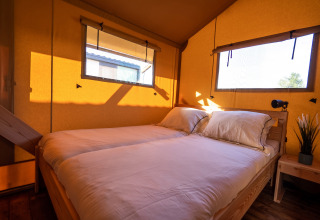 Dormitorio en la tienda safari SunLodge Pamoja&Kambi en Camping Terme Catez, Eslovenia, al atardecer.