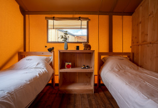 Interior de una tienda safari SunLodge Pamoja&Kambi en Camping Terme Catez, Eslovenia, con dos camas individuales.