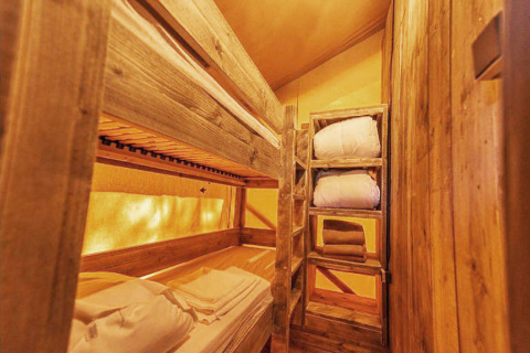 Houten stapelbedden en rekken met beddengoed in een gezellige kamer van SunLodge Pamoja&Kambi, Camping Terme Catez.