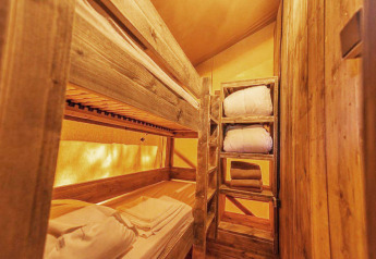 Houten stapelbedden en rekken met beddengoed in een gezellige kamer van SunLodge Pamoja&Kambi, Camping Terme Catez.