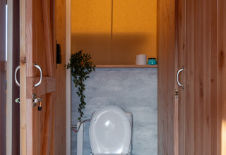 Houten toilet met wit sanitair in SunLodge Taiga, Camping Terme Catez, Slovenië.