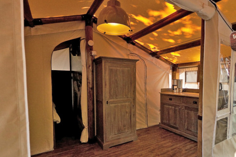 Interior de una tienda safari SunLodge Jungle con muebles de madera en Camping Vilanova Park, España.
