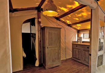 Interno di una tenda safari SunLodge Jungle con mobili in legno al Camping Vilanova Park, Spagna.