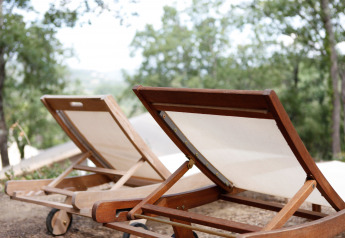 Twee houten ligstoelen bij de SunLodge Jungle safaritent op Camping Vilanova Park in Spanje, omgeven door groen.