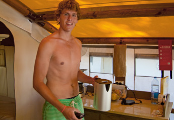 Jonge man met groene zwemshort, zonder hemd, in een SunLodge Jungle safaritent op Camping Vilanova Park, Spanje.