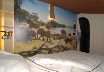 Interno della tenda safari SunLodge Jungle al Camping Vilanova Park in Spagna, con murale di elefanti.