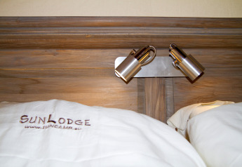 Biancheria da letto con logo SunLodge e luci da lettura su testiera in tenda safari al Camping Vilanova Park, Spagna