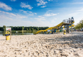 Spiaggia con scivolo giallo sul lago al Vakantiepark Klein Strand, parco vacanze nelle Fiandre Occidentali, Belgio.