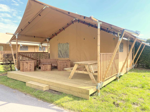 Safarizelt mit Holzterrasse und Sitzbereich außen im Vakantiepark Klein Strand, Westflandern, Belgien.