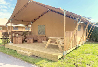Safarizelt mit Holzterrasse und Sitzbereich außen im Vakantiepark Klein Strand, Westflandern, Belgien.