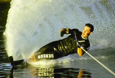 Persoon waterskiet op een meer, grote waterspray bij Vakantiepark Klein Strand in België.