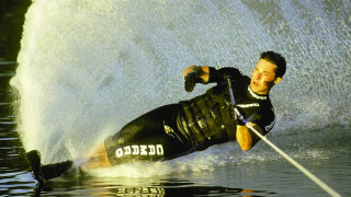 Persona practicando esquí acuático en un lago, creando una gran estela en Klein Strand, Bélgica.
