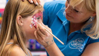Niña recibiendo pintura facial de una artista en el parque vacacional Klein Strand en Flandes Occidental, Bélgica.